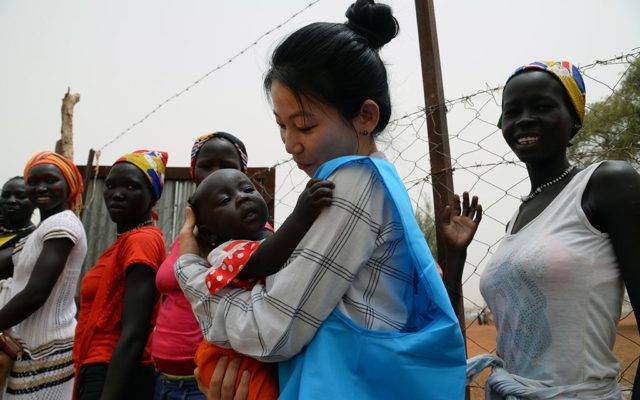 UNHCR staff Eujin Byun holds a refugee baby in her arms while the child's mother waits in the line to get the proof of registration