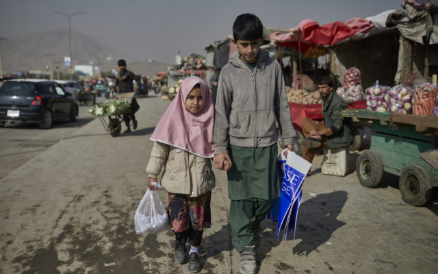 Hajira and Matiullah hold hands as they walk through a marketplace in Afghanistan