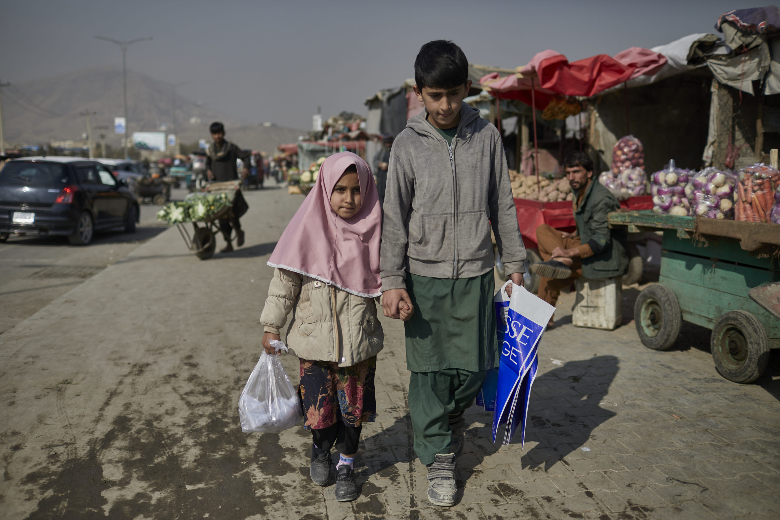 Hajira and Matiullah hold hands as they walk through a marketplace in Afghanistan