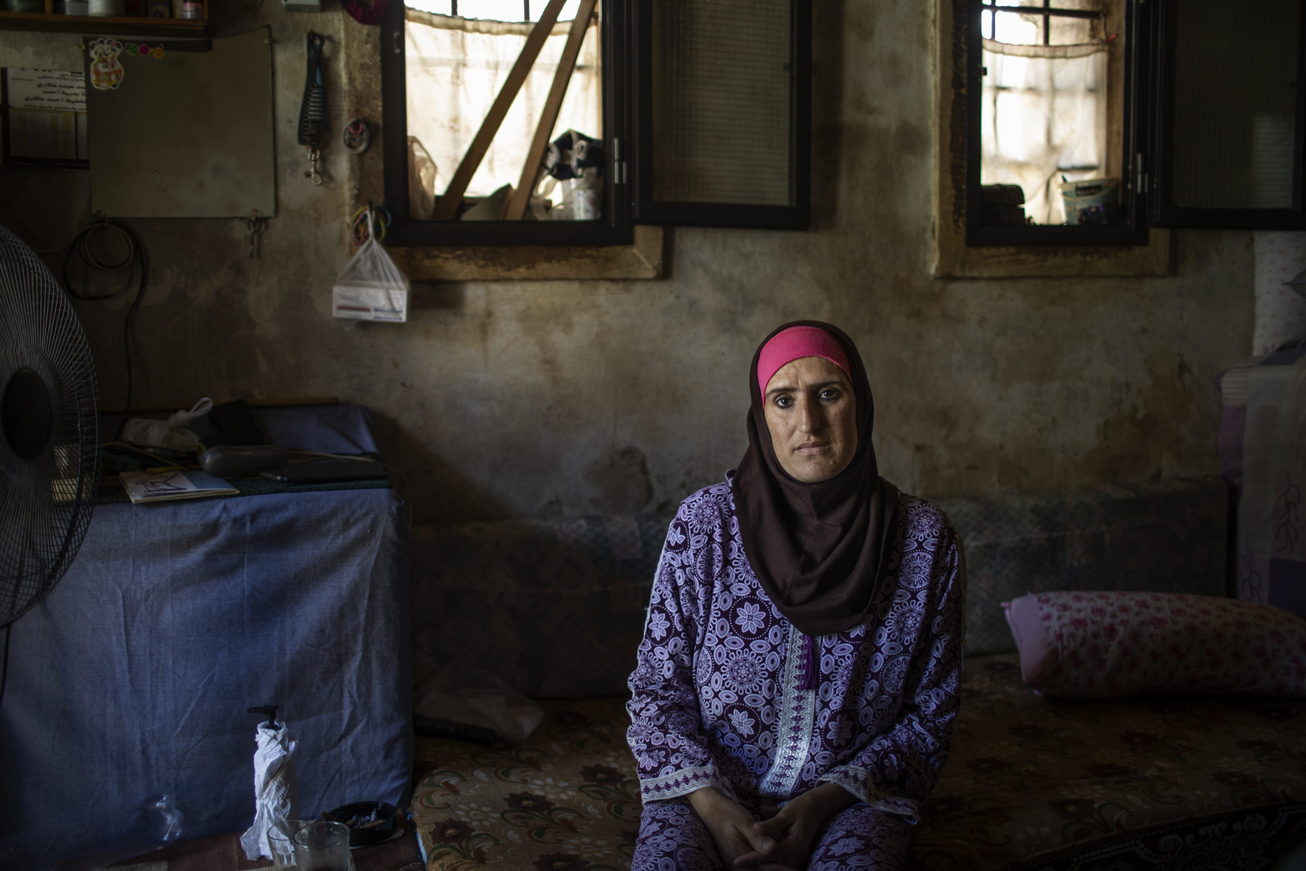 Zahida, 35, stands in front of the ruins of her house