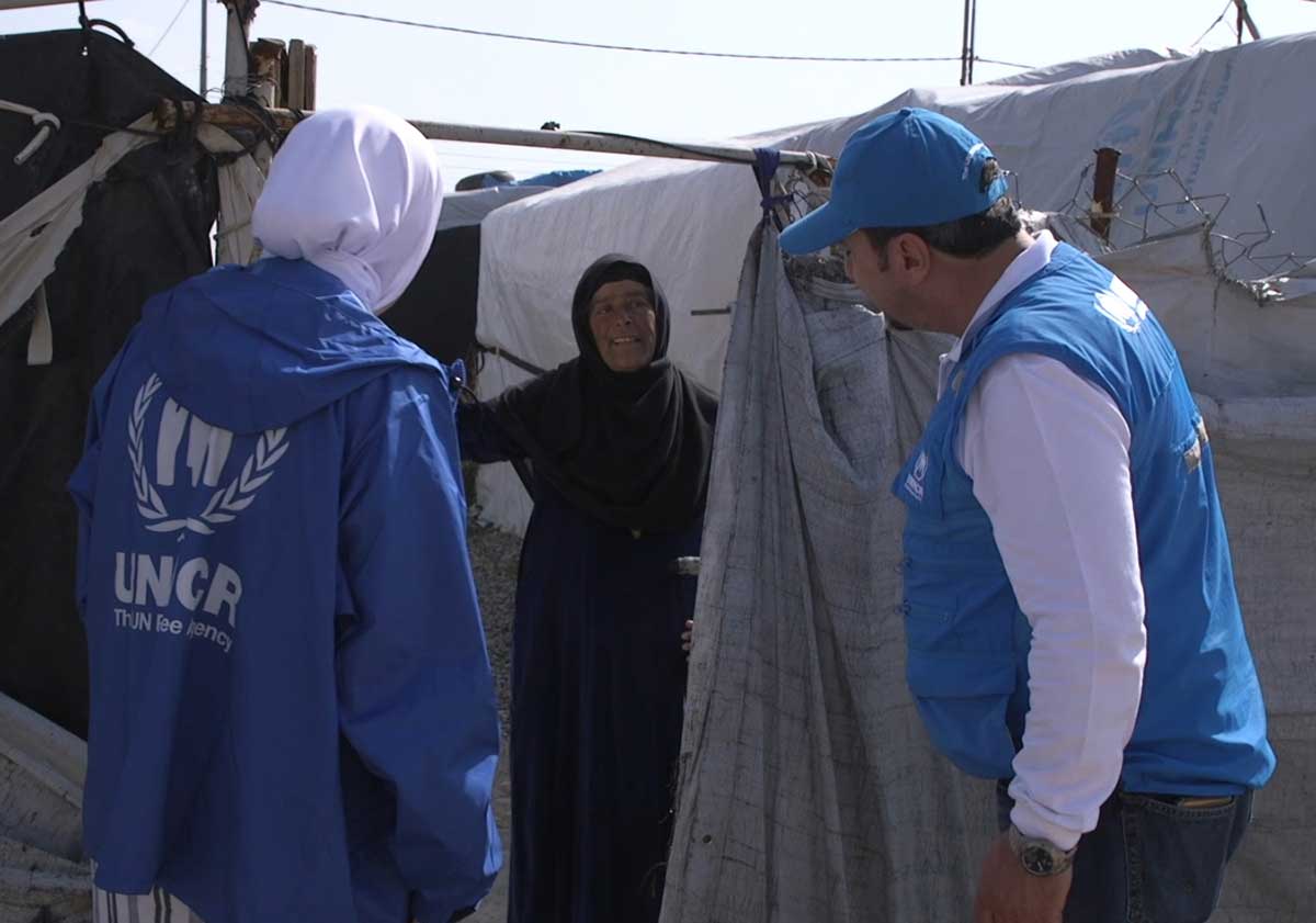 Woman in refugee camp with UNHCR workers